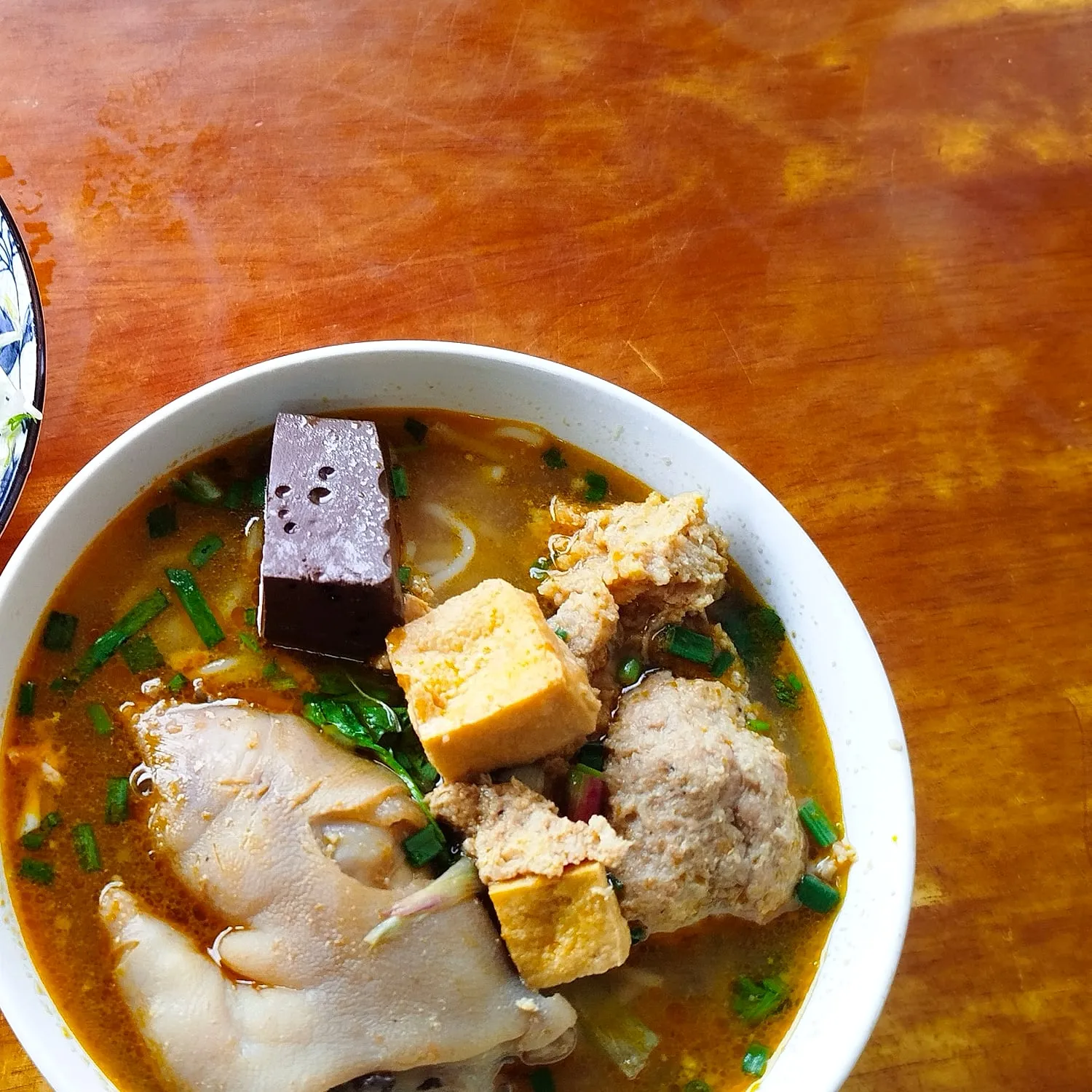 A steaming bowl of Lam’s bún riêu cua đồng on a warm wooden table