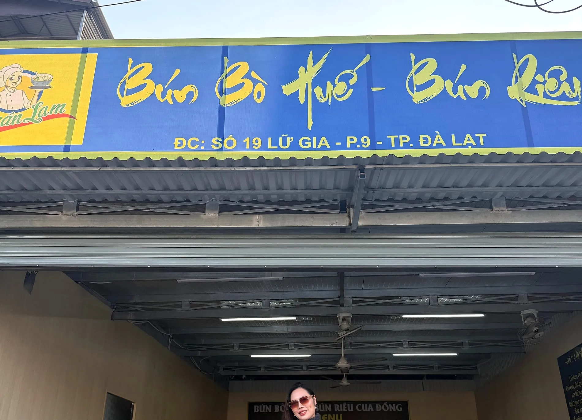 The blue and yellow shopfront of Quán Lam on Lữ Gia street in Đà Lạt